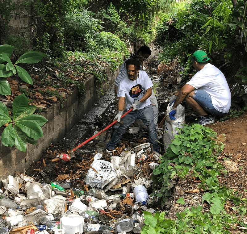 Volunteers showcasing Coca-Cola recycling bins at a sustainability event inside a shopping mall.