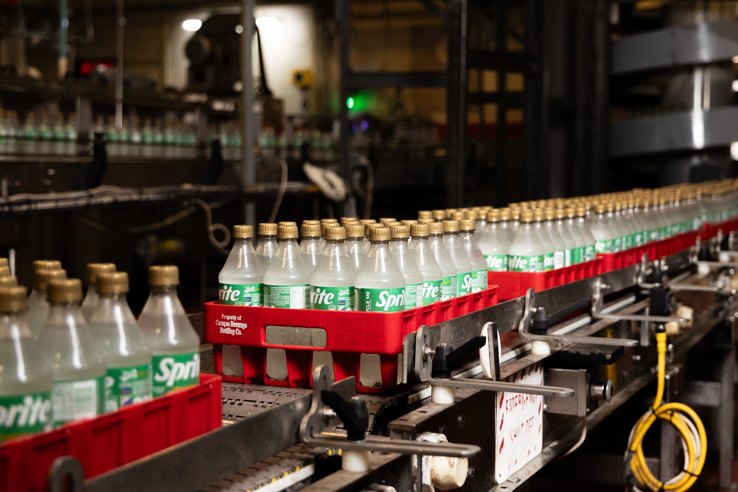 Sprite glass bottles aligned on a conveyor belt in the bottling plant, demonstrating efficiency and clean production.