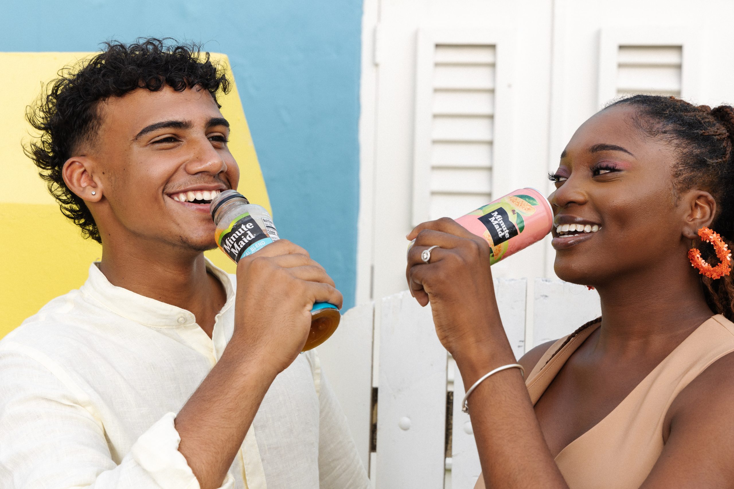 Two young people enjoying Minute Maid drinks, smiling and sharing a joyful moment outdoors, reflecting brand freshness.